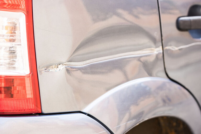 Damaged vehicle body panel with dent and crease requiring auto body repair or panel replacement evaluation