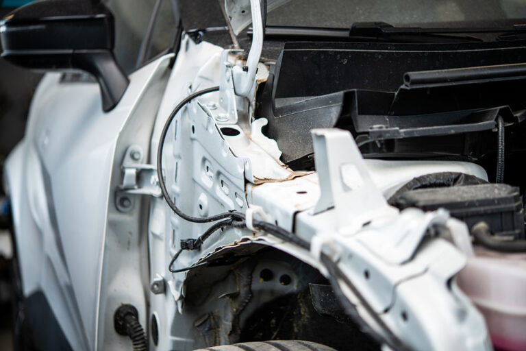 Auto body technician inspecting hidden vehicle damage after teardown during the collision repair process